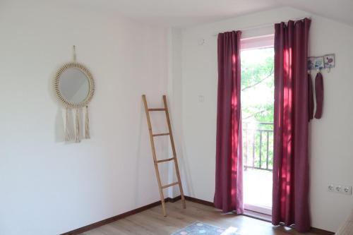 a room with red curtains and a ladder and a mirror at House Trebević ReStart in Petruše