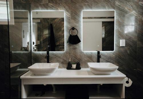 a bathroom with two sinks and two mirrors at VillaAmor in Arorangi