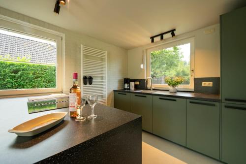 a kitchen with green cabinets and a counter with wine glasses at De Duiker in Wolphaartsdijk