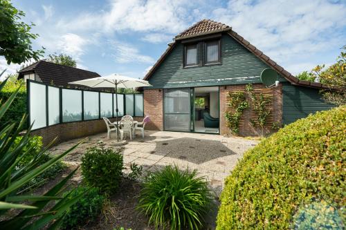 a house with a patio with an umbrella at De Duiker in Wolphaartsdijk