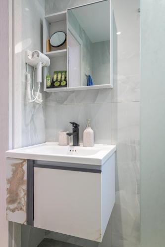 a white bathroom with a sink and a mirror at Vounala Studio in Pollonia