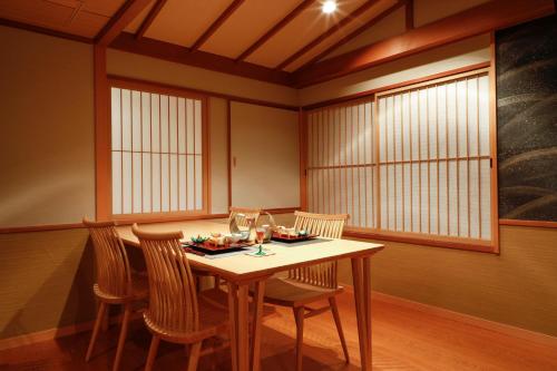 a dining room with a table and chairs and windows at Sun Urashima Yuki no Sato in Toba