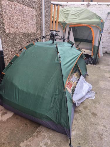 a green tent sitting on the ground next to a building at Phoenix Nights Guest House in Barrow in Furness