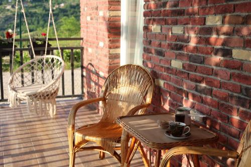 two wicker chairs and a table on a porch at House Trebević ReStart in Petruše