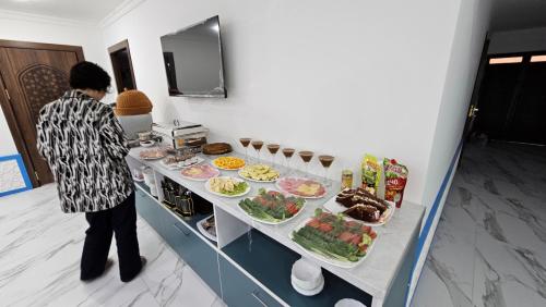 eine Frau steht vor einem Buffet mit Essen in der Unterkunft Mumtoz East Hotel in Buxoro