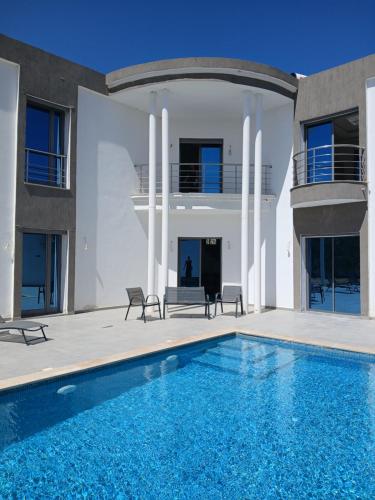 a villa with a swimming pool and a house at Villa Olivier rond point du rendez-vous, Midoun in Djerba