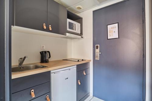 a small kitchen with a sink and a microwave at Appart Hotel Odalys City Aix en Provence L'Atrium in Aix-en-Provence