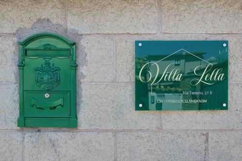 a green post box on a brick wall with a sign at Villa Lella - Pantheon in Ardea