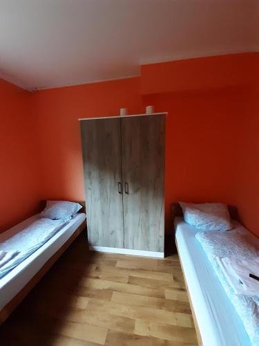 two beds in a room with an orange wall at 2-Rent Group Hostel Rooms&Apartments TUB19A in Munich