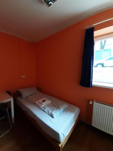 a bedroom with orange walls and a bed with a window at 2-Rent Group Hostel Rooms&Apartments TUB19A in Munich