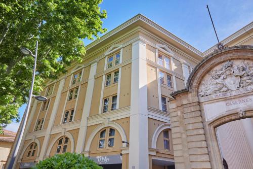 a large yellow building with a tree at Appart Hotel Odalys City Aix en Provence L'Atrium in Aix-en-Provence