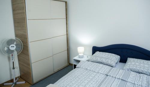 a bedroom with a blue bed and a fan at Adi apartment in town centar in Konjic