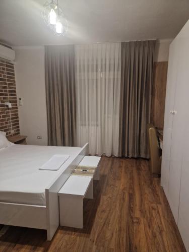 a bedroom with a white bed and a table at Shkodra 27 center house in Shkodër