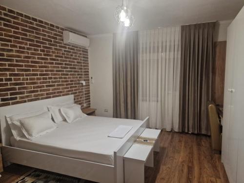 a bedroom with a white bed and a brick wall at Shkodra 27 center house in Shkodër