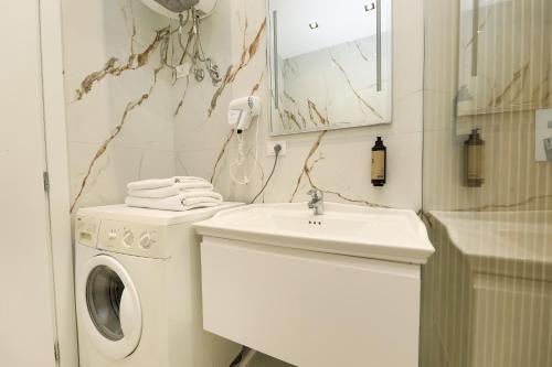 a white bathroom with a washing machine and a sink at Rezidenca Panorama Apartments in Vlorë