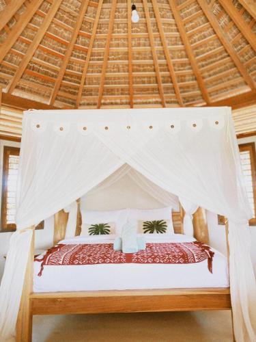 a bedroom with a bed with a mosquito net at Oeseli Beach Bungalow in Pulau Helihana