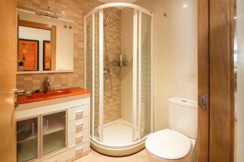 a bathroom with a shower and a toilet and a sink at Apto Llanes Piscina y Playa – El Recreo de Celorio in Celorio