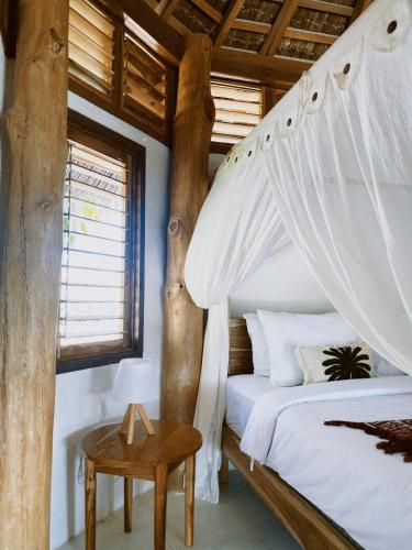 a bedroom with a canopy bed and a table at Oeseli Beach Bungalow in Pulau Helihana