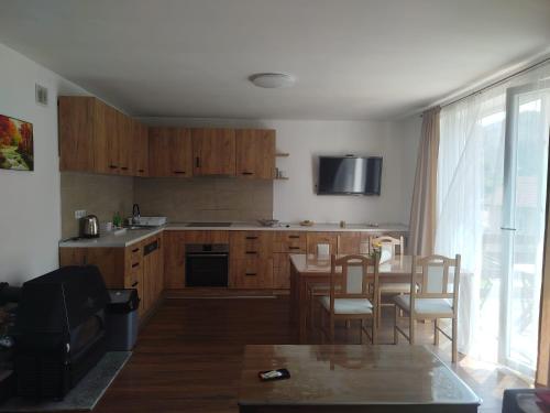 a kitchen with wooden cabinets and a table with chairs at Apartman ANNA in Jajce