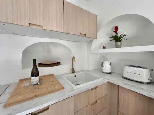 - une cuisine avec un évier et une bouteille de vin dans l'établissement La Maison du Figuier, à Cournanel