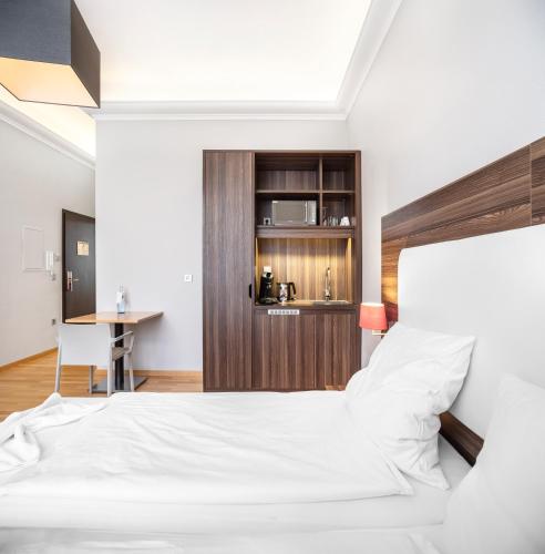 a bedroom with a white bed and a desk at BoardingWorld Heidelberg in Heidelberg