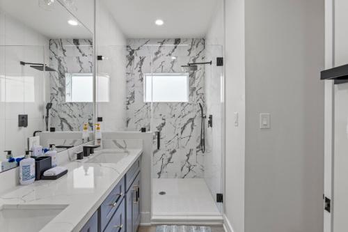 a white bathroom with two sinks and a shower at Galveston Bayside Breeze Retreat in Galveston