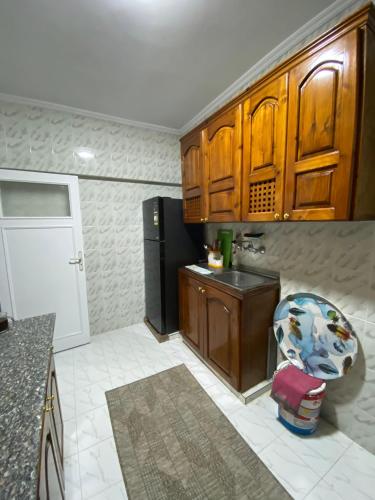 a kitchen with wooden cabinets and a refrigerator at 2BR ground chalet with private garden شاليه أرضي غرفتين بحديقة خاصة in Dawwār Ḩalīs