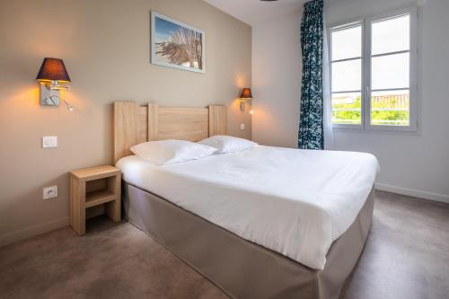 a bedroom with a large white bed and a window at Résidence Odalys Rêve d'île in Rivedoux-Plage