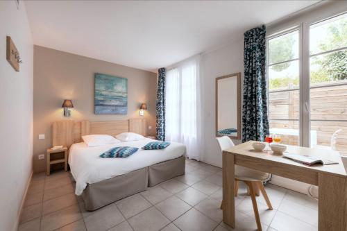 a hotel room with a bed and a table and a desk at Résidence Odalys Rêve d'île in Rivedoux-Plage