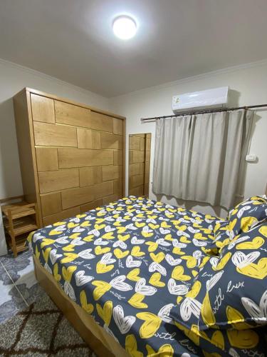 a bedroom with a bed with a blue and yellow blanket at 2BR ground chalet with private garden شاليه أرضي غرفتين بحديقة خاصة in Dawwār Ḩalīs