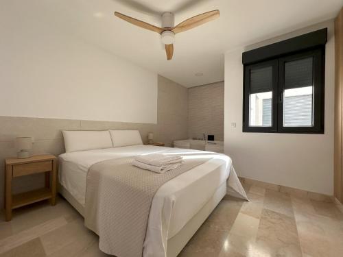 a bedroom with a white bed with a ceiling fan at Bellver Home Apartamentos in Chella