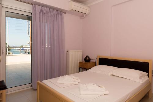 a bedroom with a bed with white sheets and a window at Eirini luxury Apartments in Keramoti