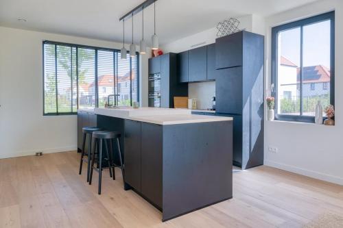a kitchen with blue cabinets and a kitchen island with stools at Beautiful 3-Bedroom Home with Garden & Parking in Deinze