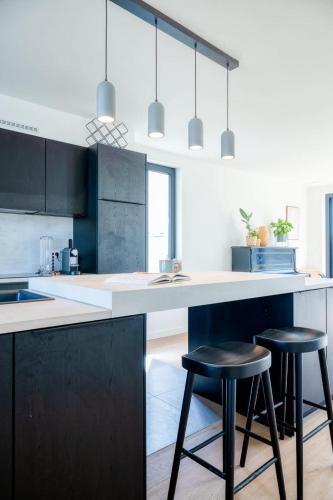 a kitchen with black cabinets and two bar stools at Beautiful 3-Bedroom Home with Garden & Parking in Deinze
