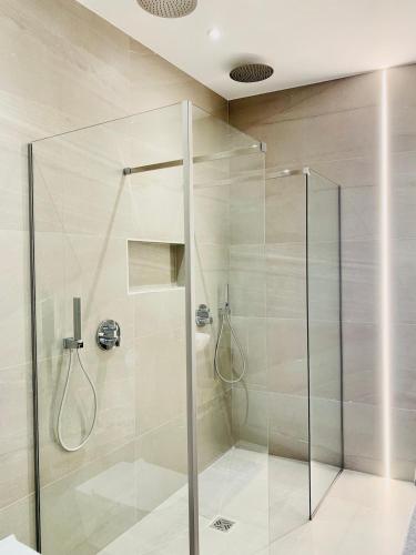 une douche avec une porte vitrée dans une salle de bain dans l'établissement VillaM with heated pool, panoramic view, sea, à Mandelieu-la-Napoule