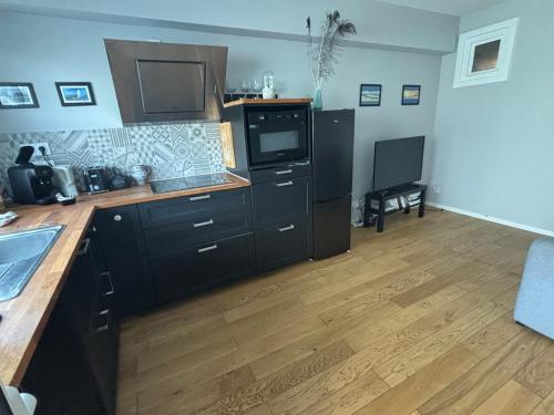 une cuisine avec des armoires noires et un plancher en bois dans l'établissement T2 RdC avec parking, plage à 50m, à Arcachon
