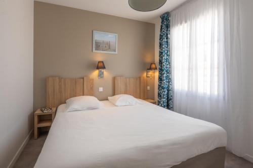 a bedroom with a large white bed and a window at Résidence Odalys Rêve d'île in Rivedoux-Plage
