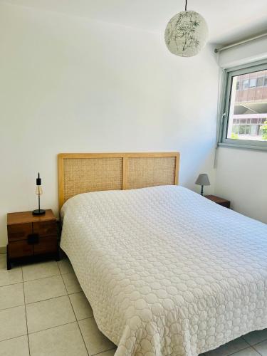 une chambre avec un grand lit blanc avec une fenêtre dans l'établissement La Major, Appartement urbain + Parking, à Marseille