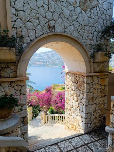 an archway in a stone wall with a view of the water at Cactus Garden Kalkan - Private Mediterranean Home at Club Patara in Kalkan