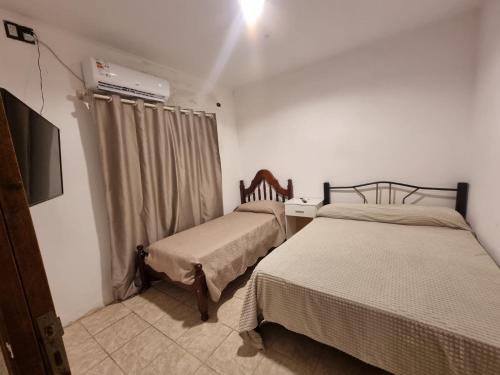 a bedroom with two beds and a television in it at Alojamiento Almendra in Paso de los Libres