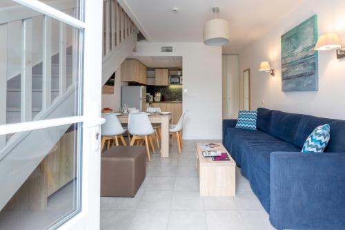 a living room with a blue couch and a kitchen at Résidence Odalys Rêve d'île in Rivedoux-Plage