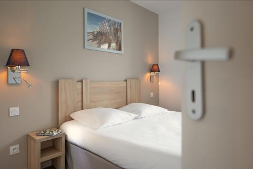 a bedroom with a bed with white sheets and two lamps at Résidence Odalys Rêve d'île in Rivedoux-Plage
