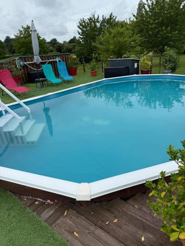 une grande piscine bleue avec des chaises et un parasol dans l'établissement Chalet cosy à Saint-Agne, 35 m² avec piscine, à Saint-Aigne