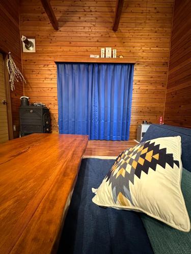 a bedroom with a wooden table and blue curtains at Hakushu hutte in Hokuto