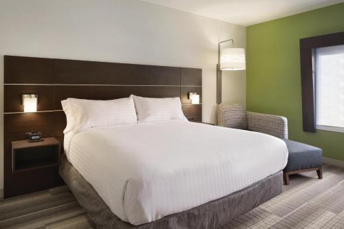 a bedroom with a large white bed and a chair at Holiday Inn Express Atlanta SW - Newnan by IHG in Newnan