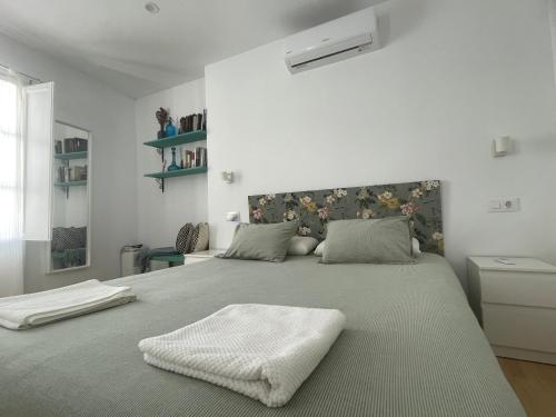 a white bedroom with a large bed with a blanket at Casa Santísimo in Vejer de la Frontera