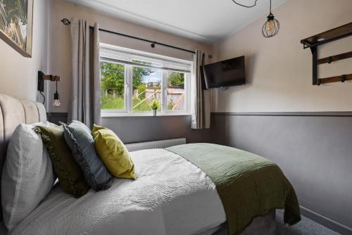 a bedroom with a bed with a window and a television at 4BR Home Near Morriston, Swansea in Swansea
