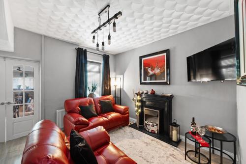 a living room with a red leather couch and a fireplace at 4BR Home Near Morriston, Swansea in Swansea