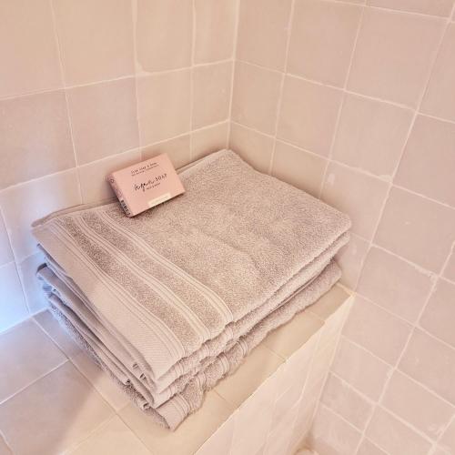 une pile de serviettes assises sur une étagère dans une salle de bains dans l'établissement Villa Les Embruns, Villa balnéaire familiale, plages à pied, à Saint-Quay-Portrieux