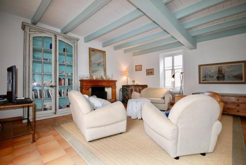 - un salon avec 2 chaises blanches et une télévision dans l'établissement 530 D La Petite Verrière Village house, à Saint-Martin-de-Ré